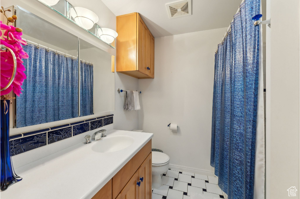 Full bathroom featuring toilet, baseboards, vanity, tasteful backsplash, and a shower with curtain