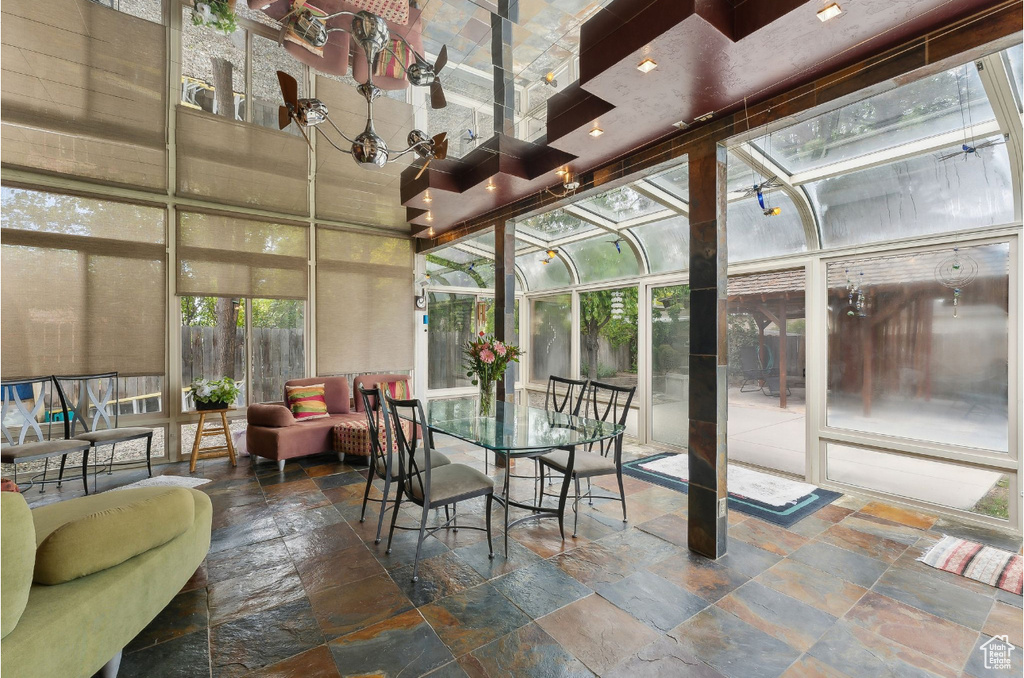 Sunroom with stone tile floors and a high ceiling