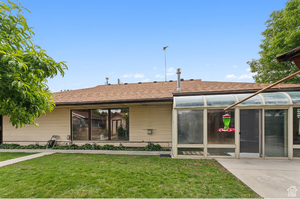 Rear view of house featuring a sunroom and a lawn