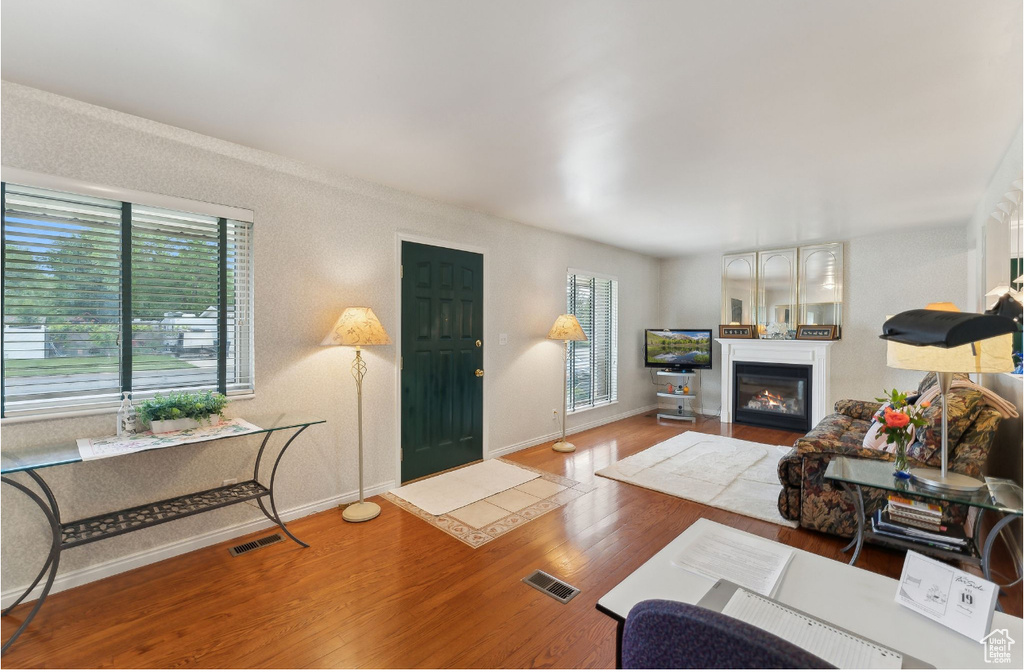 Living room with wood finished floors, a glass covered fireplace, and baseboards