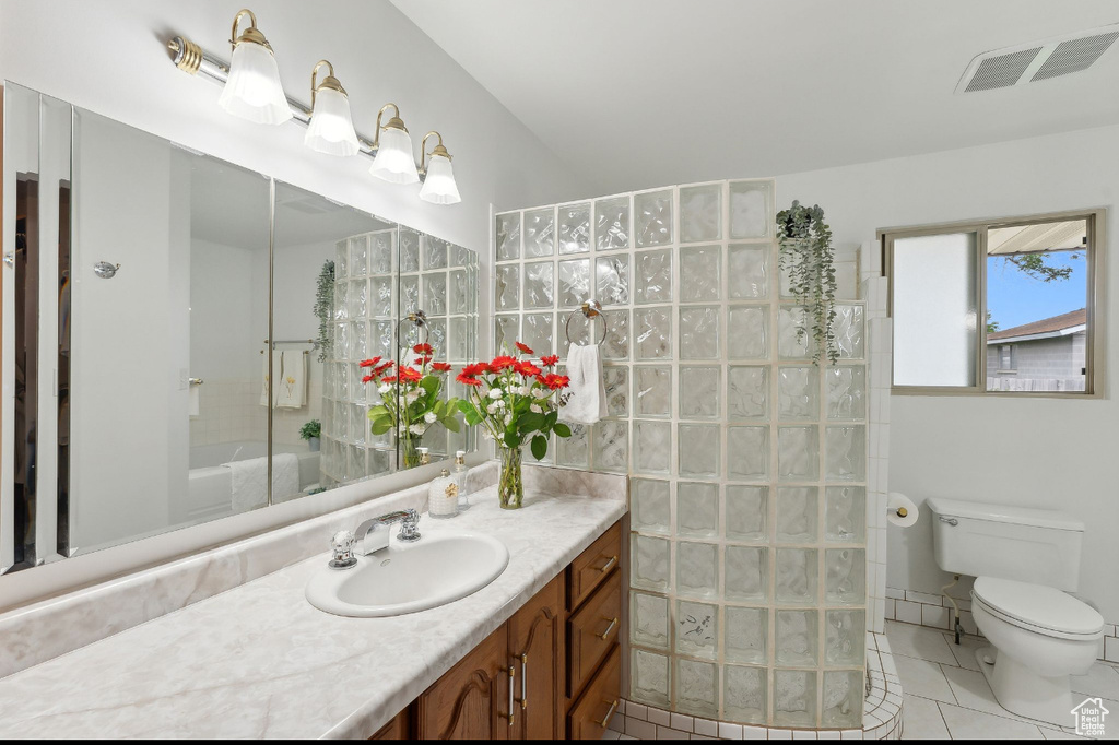 Bathroom with a walk in shower, toilet, tile patterned flooring, and vanity