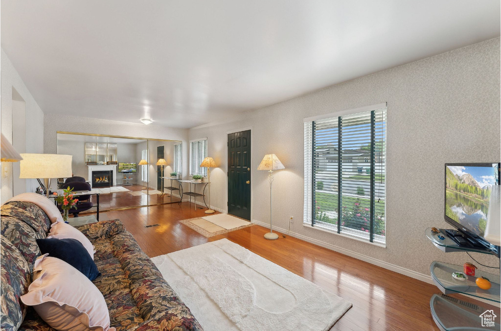 Living area with wood finished floors, baseboards, and a lit fireplace