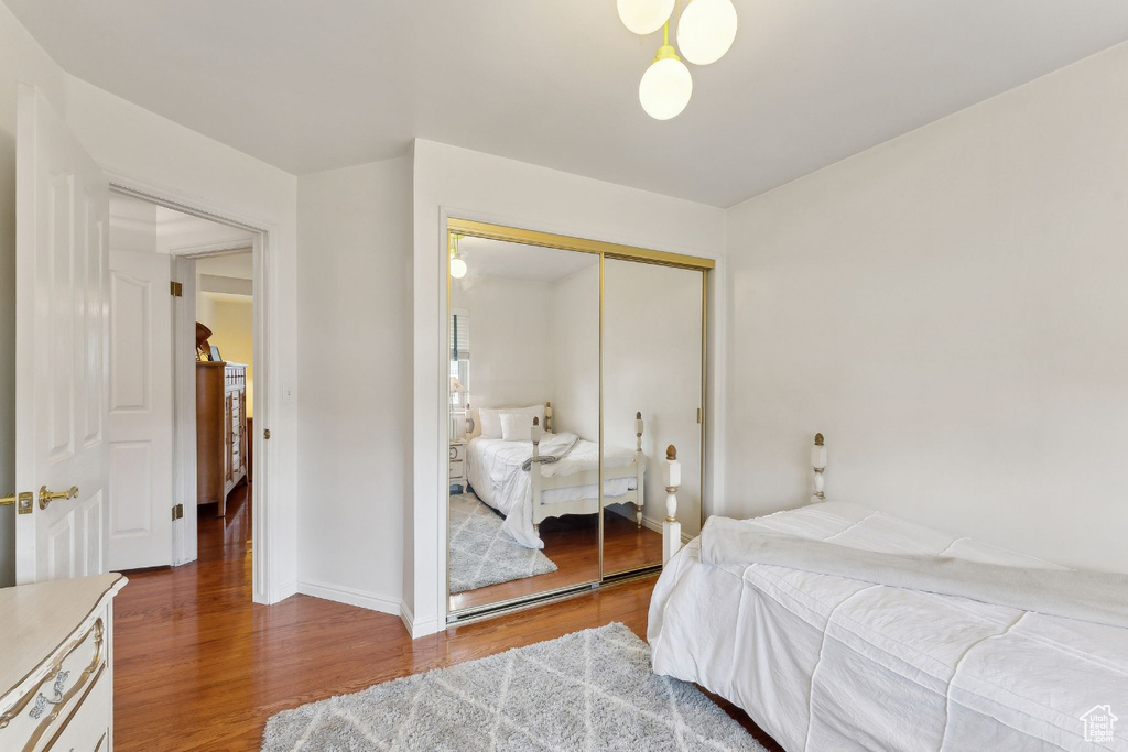 Bedroom with wood finished floors, a closet, and baseboards