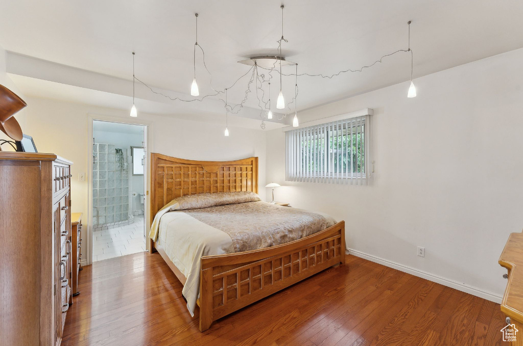 Bedroom with wood finished floors, baseboards, and ensuite bath