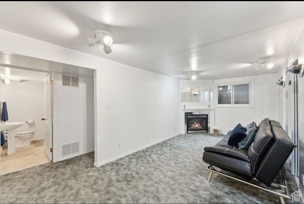 Living area with carpet floors, a glass covered fireplace, and baseboards