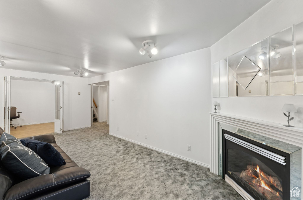 Living room with carpet, a glass covered fireplace, stairway, and baseboards