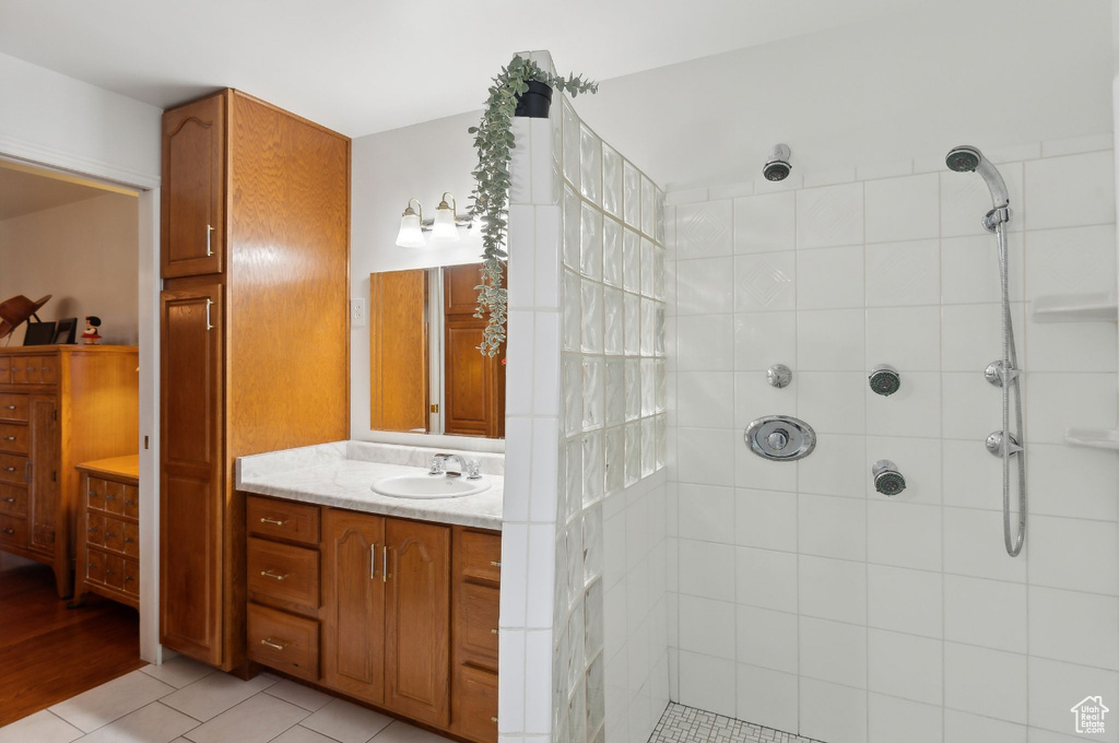 Full bath featuring a tile shower, vanity, and tile patterned flooring