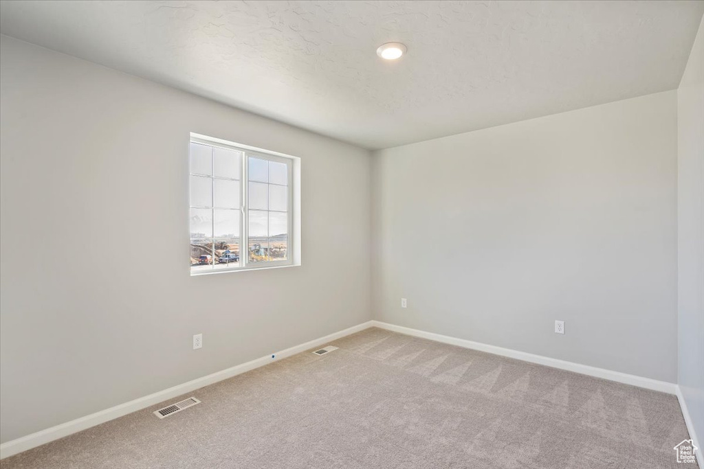 Carpeted spare room featuring baseboards