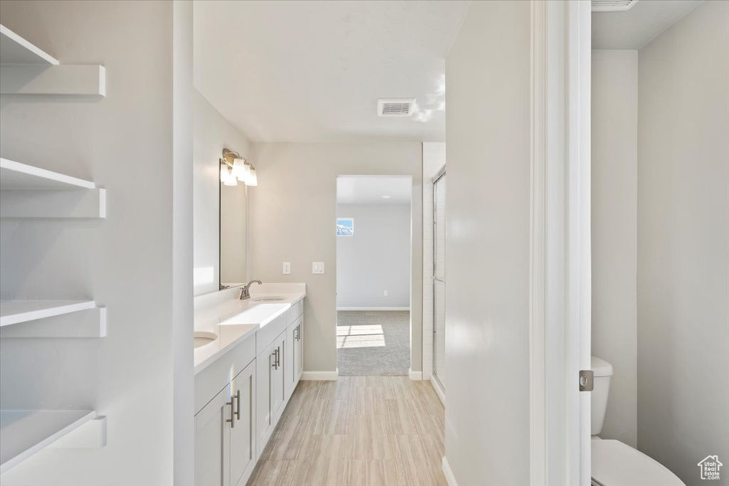 Full bathroom with double vanity, toilet, and baseboards