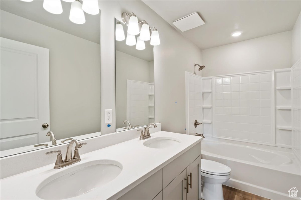 Full bathroom featuring toilet, washtub / shower combination, double vanity, and wood finished floors