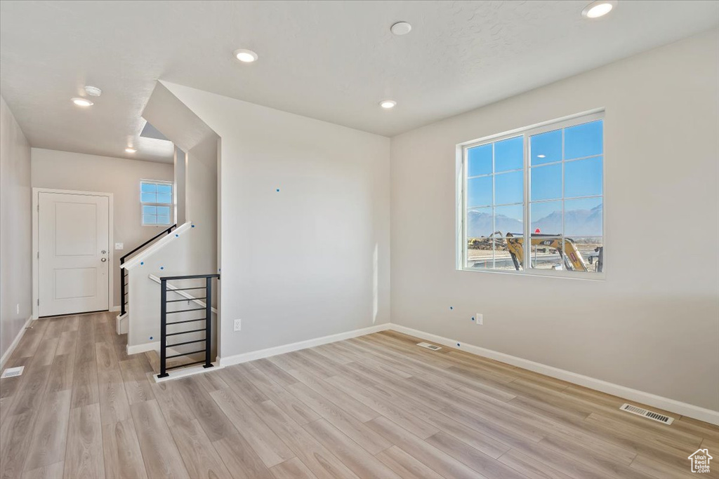 Empty room featuring light wood-style flooring, baseboards, and recessed lighting