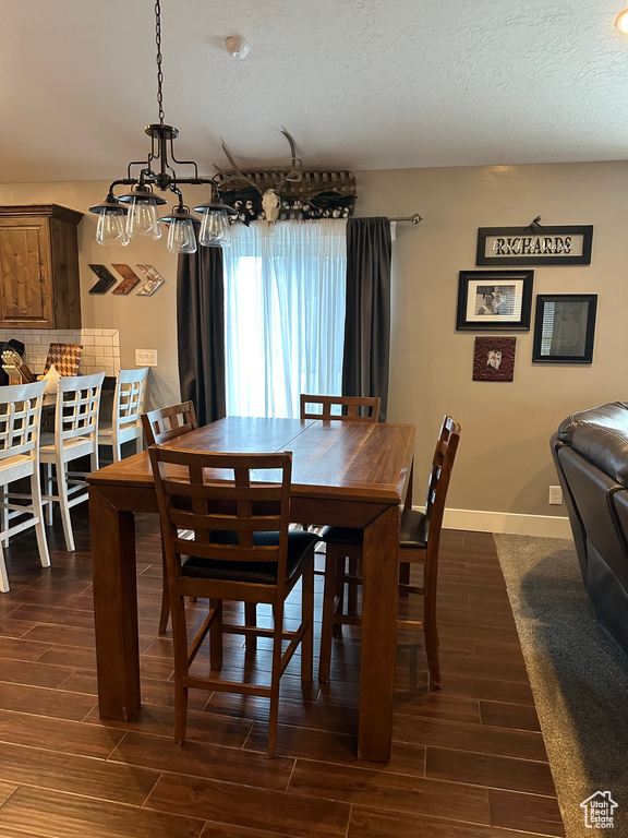 Dining area with an inviting chandelier, dark hardwood / wood-style flooring, and a textured ceiling