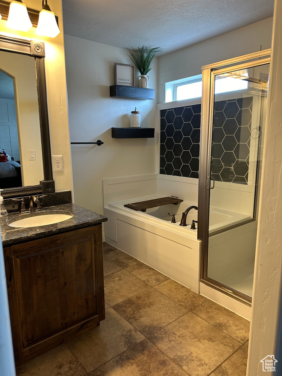 Bathroom with tile flooring, separate shower and tub, vanity, and a textured ceiling