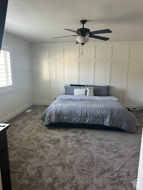 Carpeted bedroom featuring a textured ceiling and ceiling fan