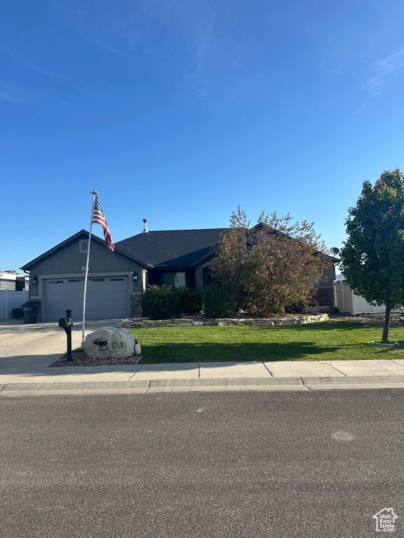 View of front of home with a garage, a front yard, and concrete driveway