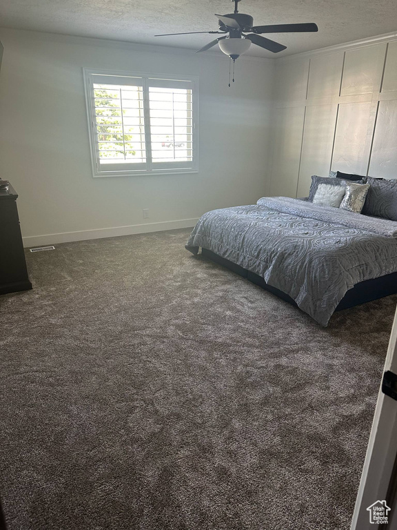 Carpeted bedroom featuring baseboards, a textured ceiling, and a ceiling fan