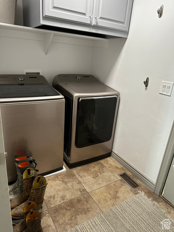 Laundry room featuring independent washer and dryer, cabinets, light tile floors, and washer hookup
