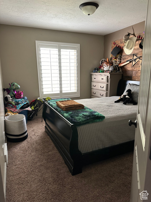 Bedroom with a textured ceiling and dark colored carpet