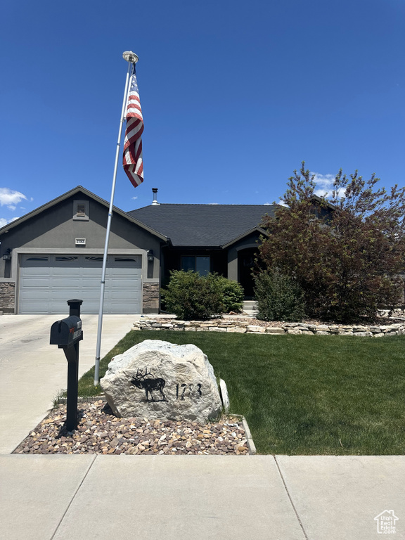 Ranch-style house featuring concrete driveway, an attached garage, stone siding, and a front yard