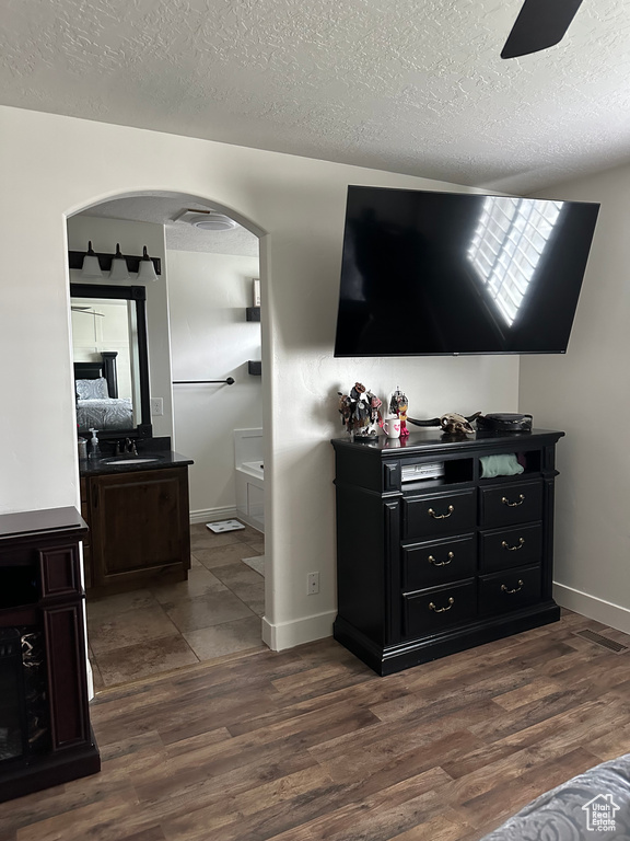 Living room with ceiling fan, sink, a textured ceiling, and dark tile floors