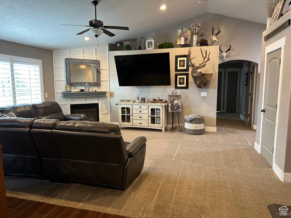 Carpeted living room with lofted ceiling and ceiling fan