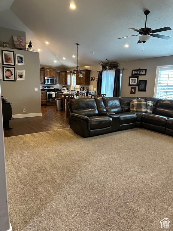 Living room featuring lofted ceiling, dark colored carpet, and ceiling fan