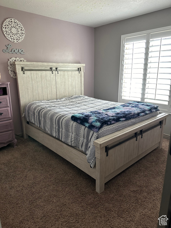Bedroom featuring dark carpet and a textured ceiling