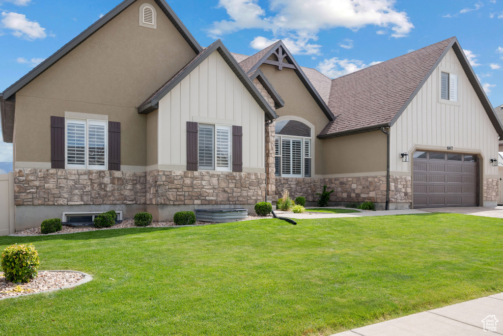 View of front of home featuring stone siding, a front lawn, and board and batten siding