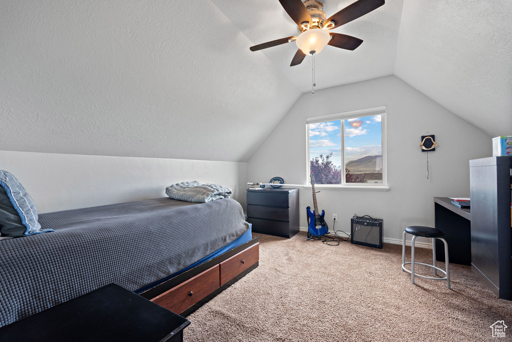 Carpeted bedroom featuring vaulted ceiling, a textured ceiling, ceiling fan, and baseboards
