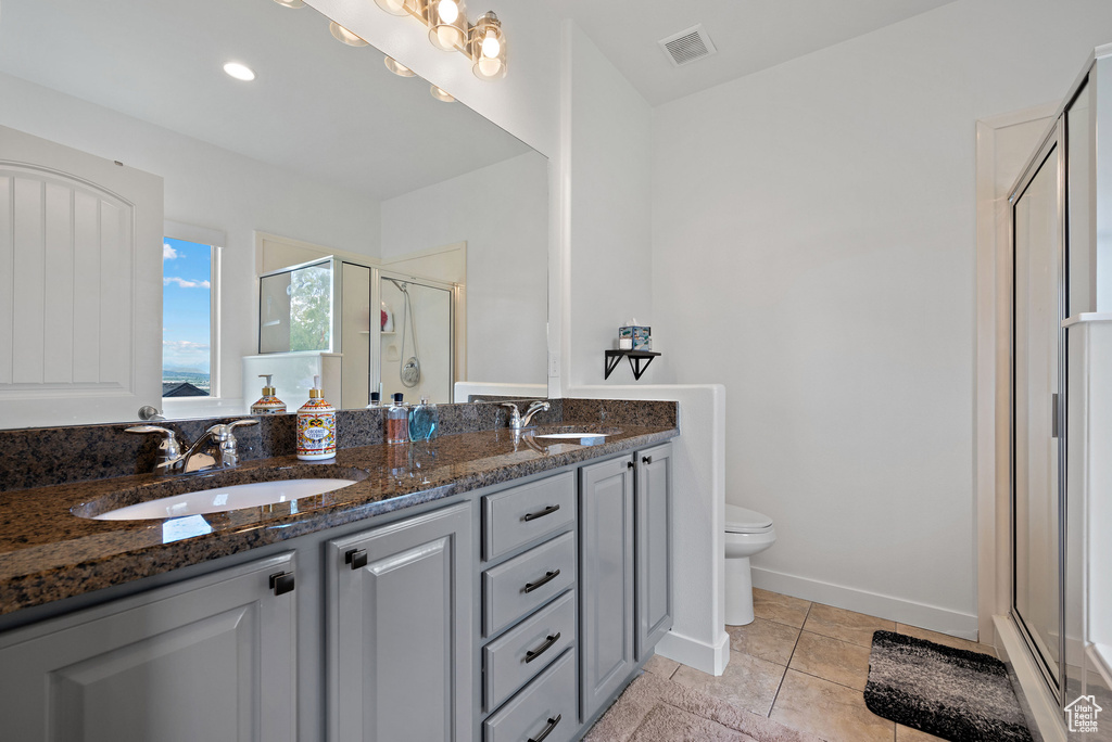 Full bath featuring a stall shower, double vanity, toilet, and tile patterned floors