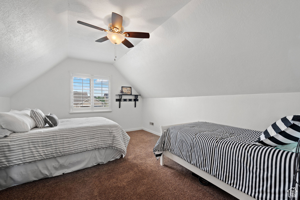 Bedroom featuring carpet floors, lofted ceiling, baseboards, a ceiling fan, and a textured ceiling