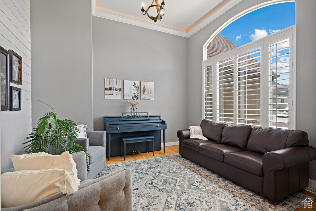 Living room with wood finished floors, ornamental molding, and a chandelier