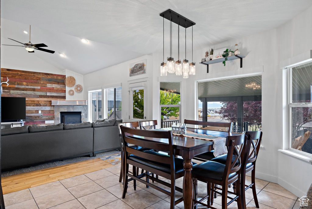 Tiled dining area featuring a tiled fireplace, a ceiling fan, and high vaulted ceiling