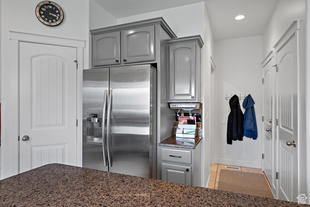 Kitchen with stainless steel refrigerator with ice dispenser, gray cabinetry, dark stone counters, recessed lighting, and tile patterned floors
