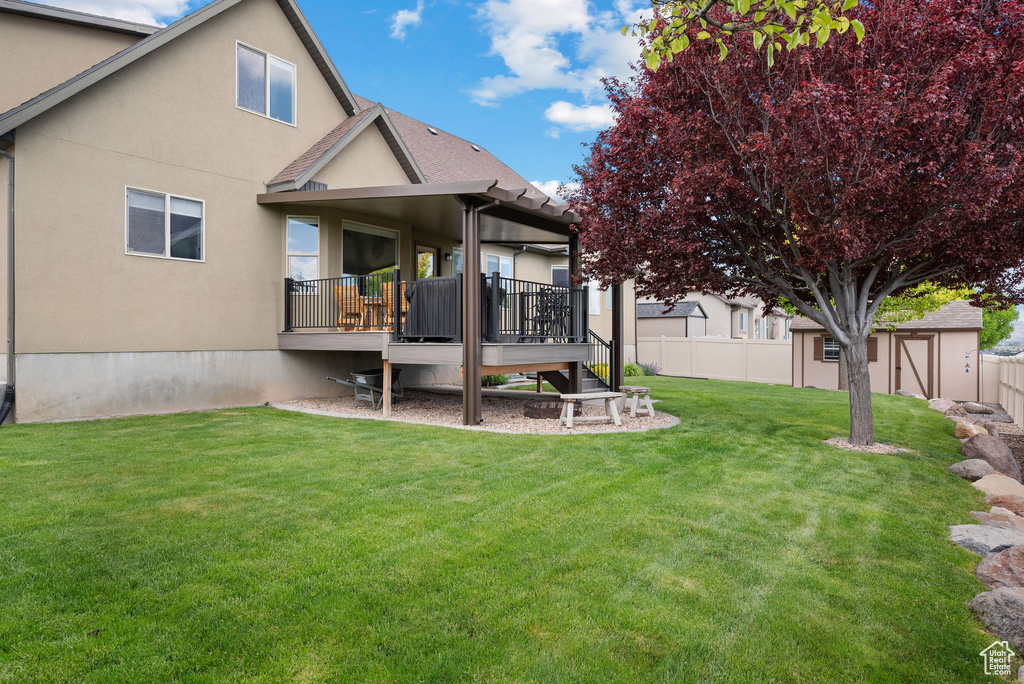 Back of property with a wooden deck, stucco siding, and roof with shingles
