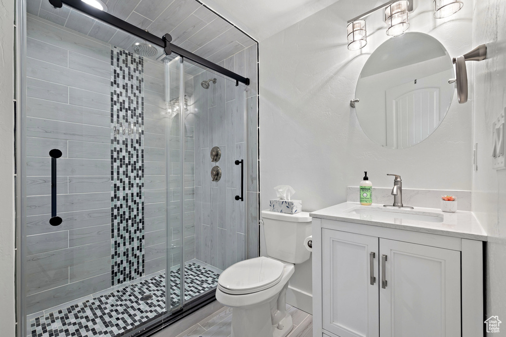 Full bath with toilet, a stall shower, and vanity