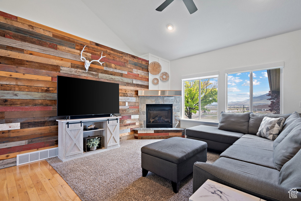 Living area with wooden walls, a glass covered fireplace, ceiling fan, hardwood / wood-style flooring, and recessed lighting
