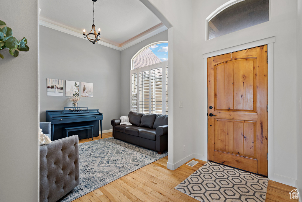 Entrance foyer featuring a chandelier, arched walkways, hardwood / wood-style floors, crown molding, and baseboards