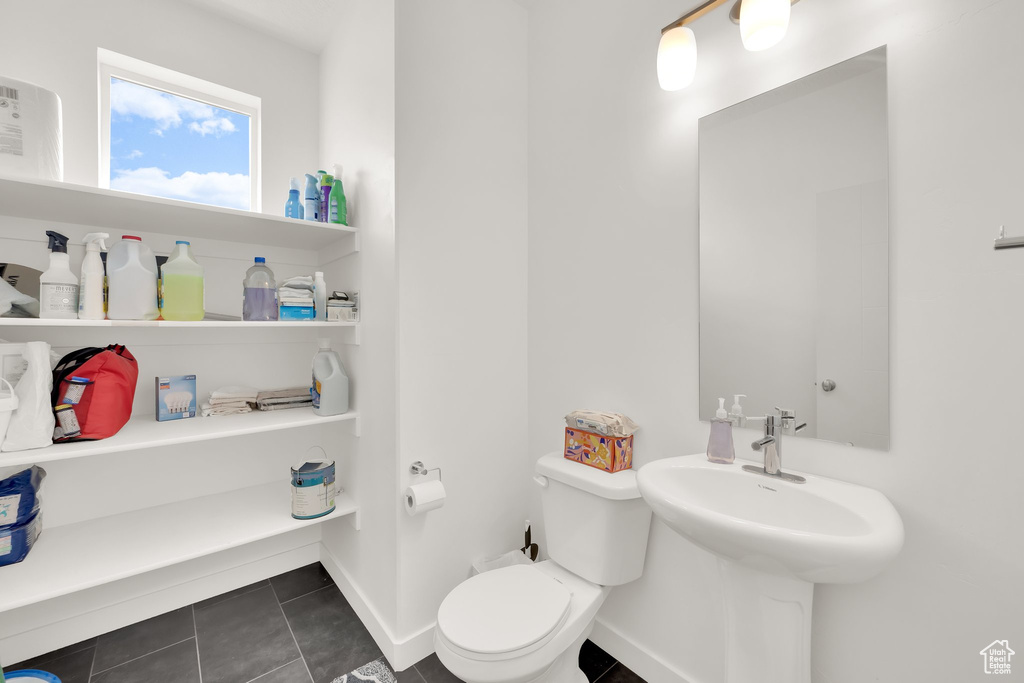 Bathroom with toilet, tile patterned floors, and baseboards