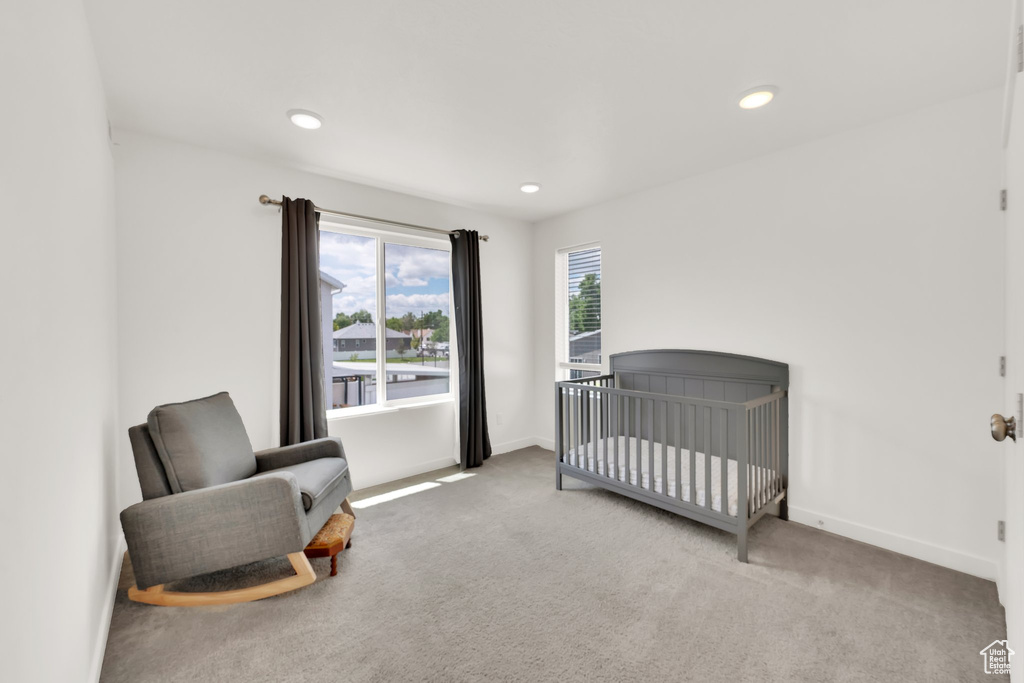 Carpeted bedroom featuring baseboards, recessed lighting, and a crib