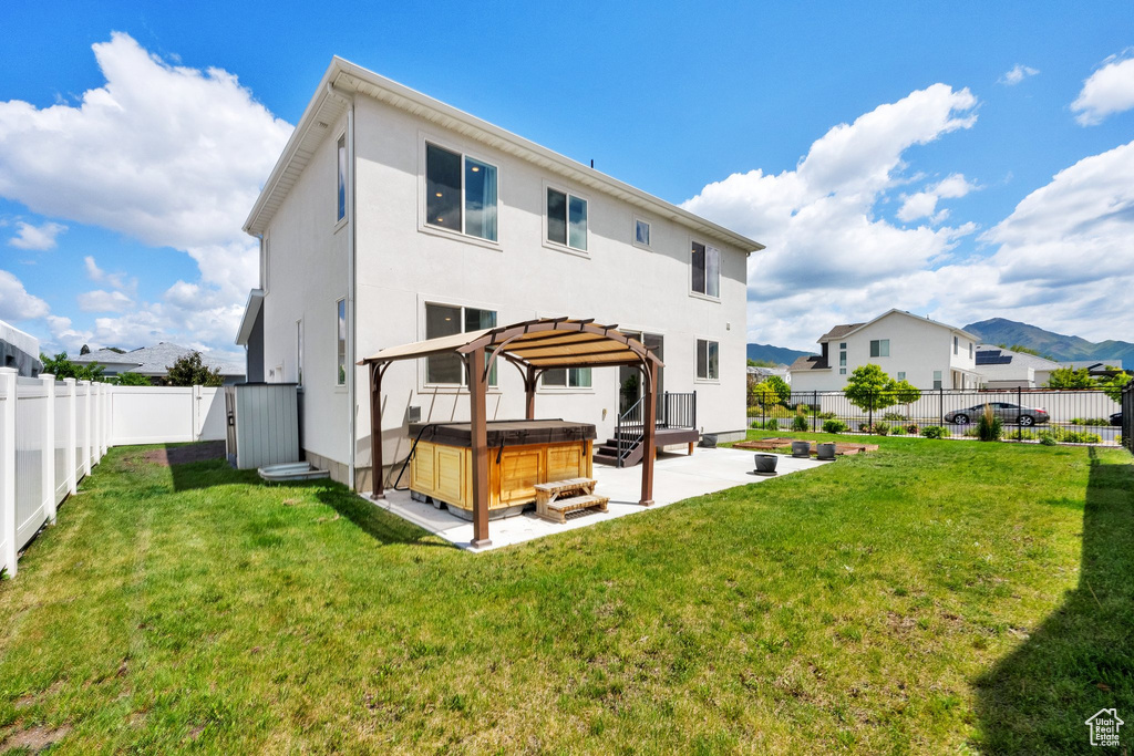 Rear view of property featuring a hot tub, a patio, stucco siding, and a residential view