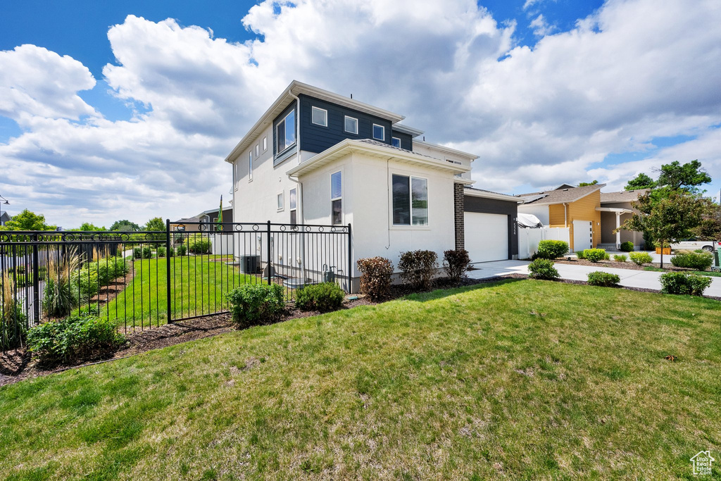 View of front of house featuring an attached garage, central AC unit, driveway, and stucco siding