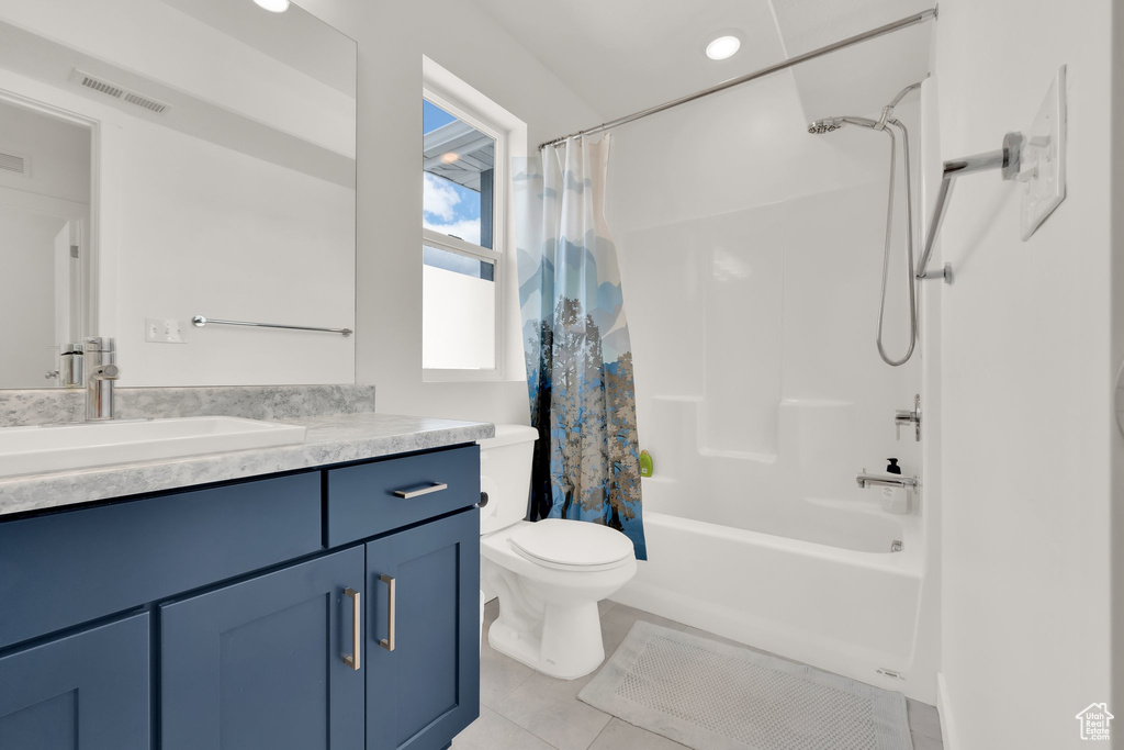 Bathroom with tile patterned floors, toilet, vanity, and shower / bathtub combination with curtain