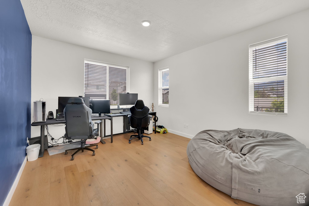 Office with wood finished floors, baseboards, and a textured ceiling