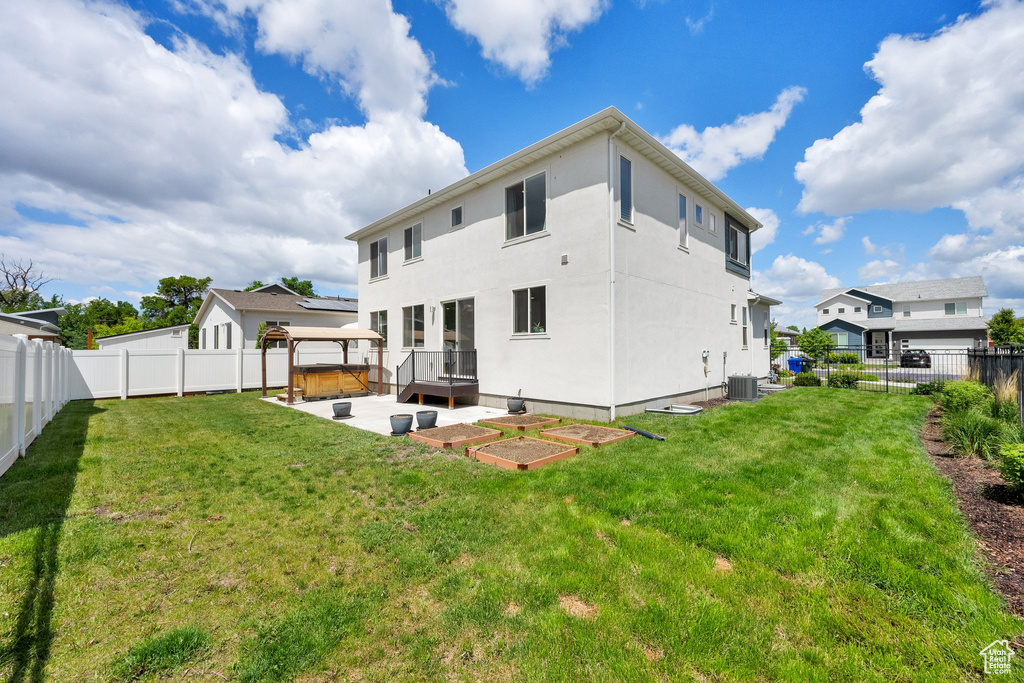 Rear view of property with central AC unit, a hot tub, a patio, stucco siding, and a gazebo