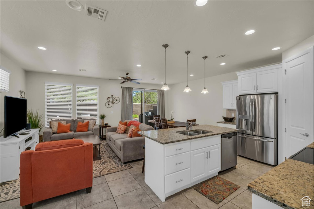 Kitchen with stainless steel appliances, a sink, open floor plan, white cabinets, and light tile patterned floors