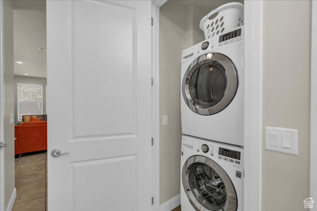 Washroom featuring stacked washer and clothes dryer, baseboards, and recessed lighting