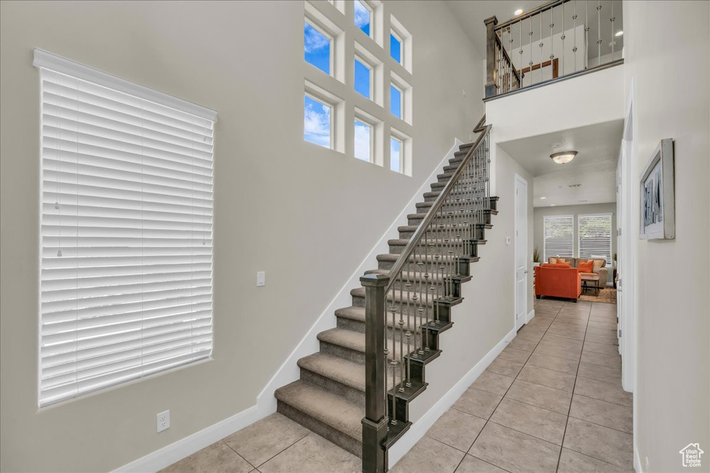 Stairway featuring tile patterned flooring, baseboards, and a high ceiling