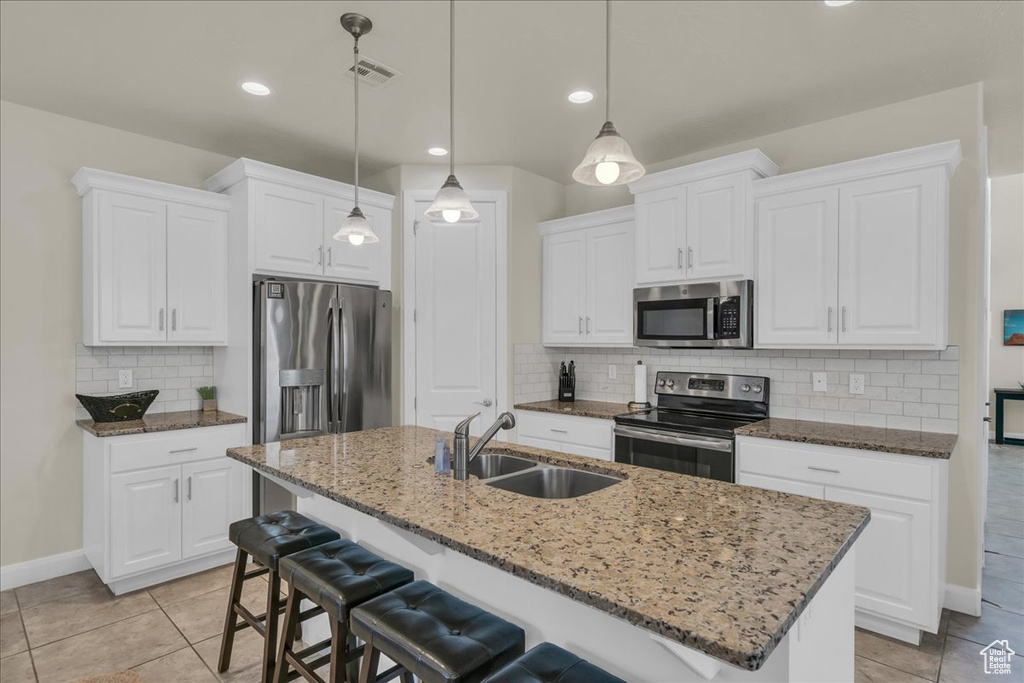 Kitchen with stainless steel appliances, a sink, baseboards, backsplash, and a kitchen bar
