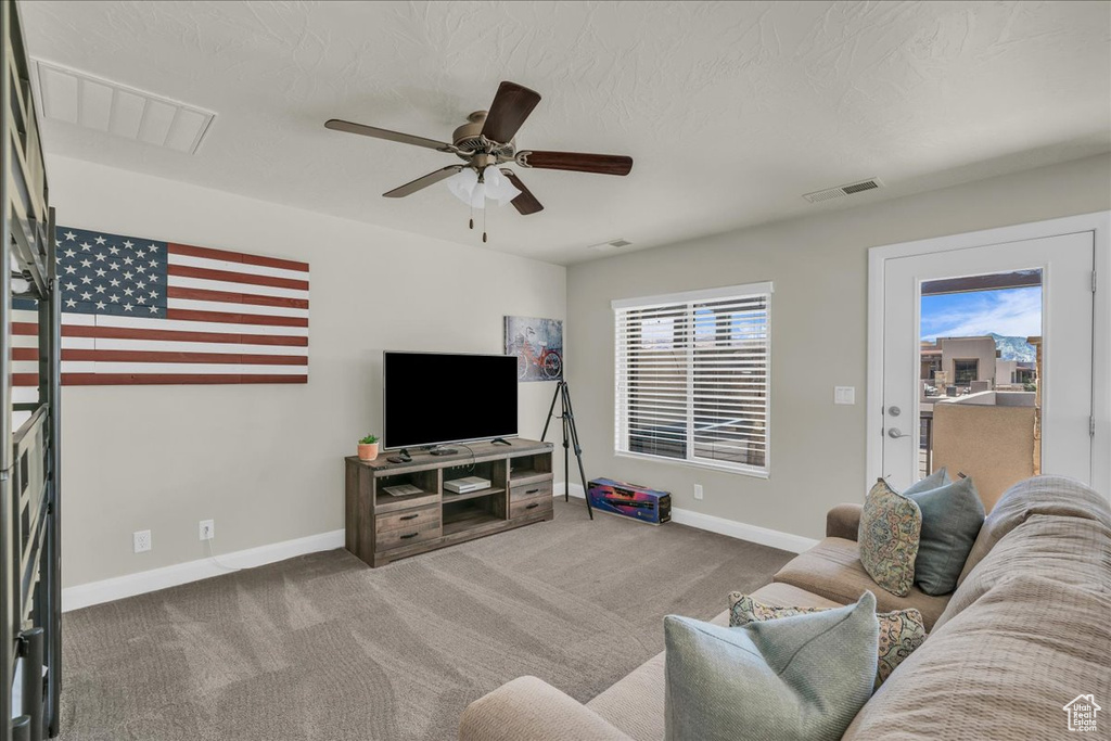 Carpeted living area with baseboards and a ceiling fan